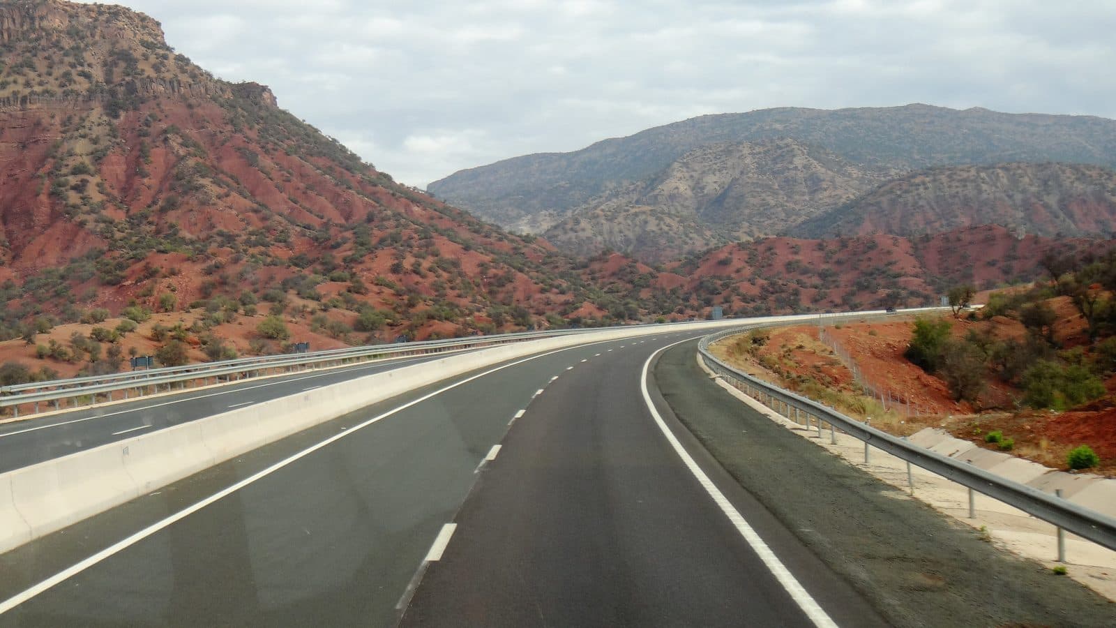 A wide road crossing the red hills of Chichaoua province under a blue sky