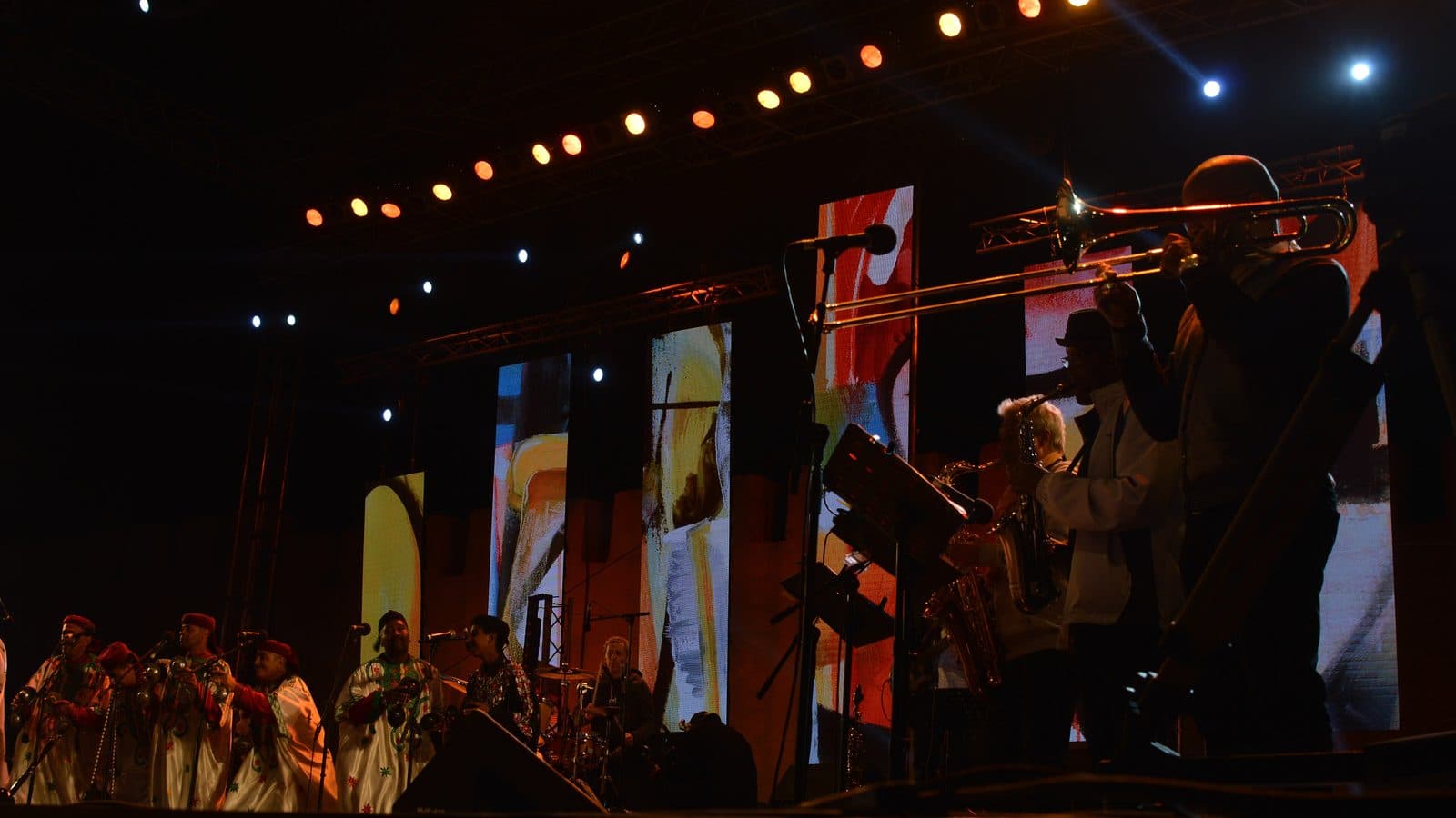 Musiciens avec trombones et saxophones sur une scène illuminée pendant le festival Gnaoua à Essaouira