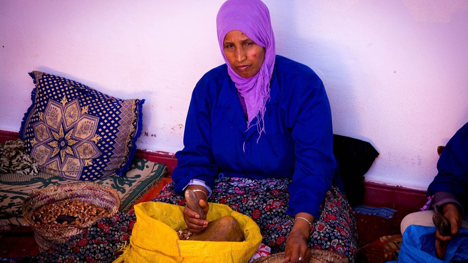 Une femme concassant des noix d'argan à la main dans une coopérative du sud-ouest marocain