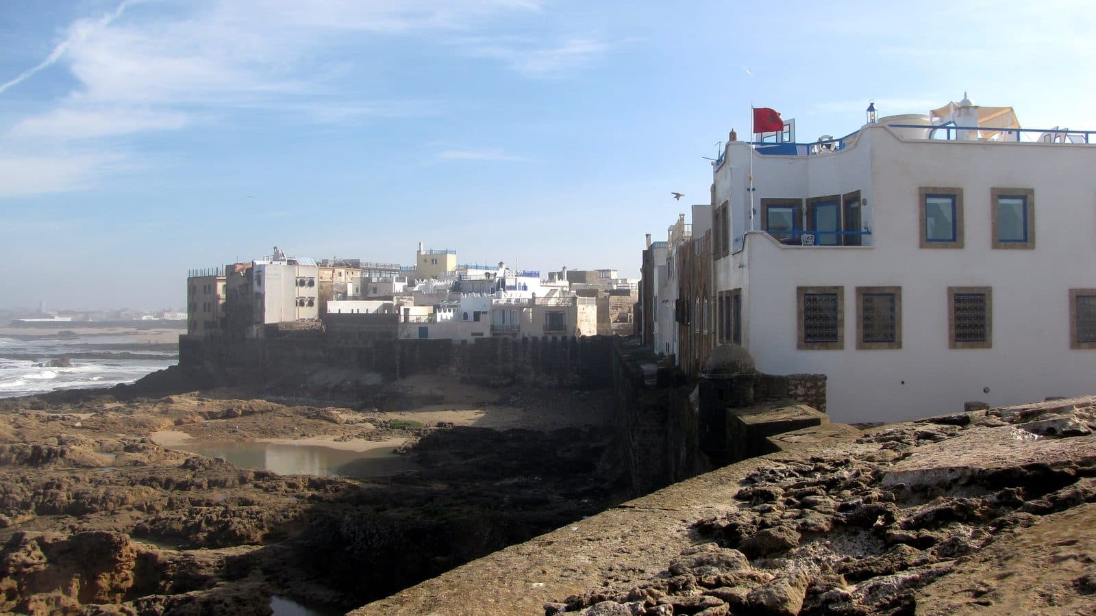 The white houses of the Essaouira medina above the rocky Atlantic shore on a sunny day