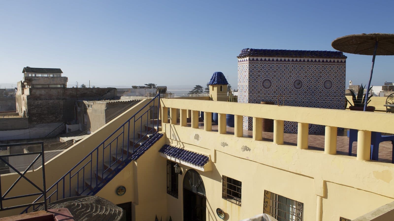 Terrasse sur le toit d’un riad de la médina d’Essaouira avec murs carrelés et vue sur la mer