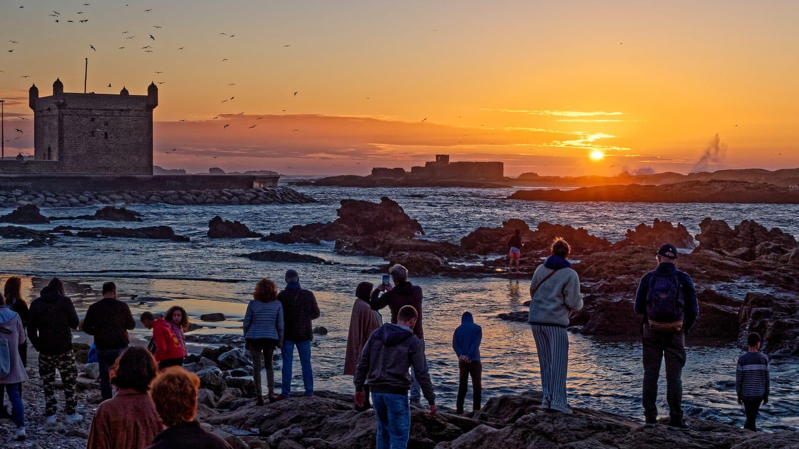 Crowd gathered on the rocks below the Skala of Essaouira to watch the sunset