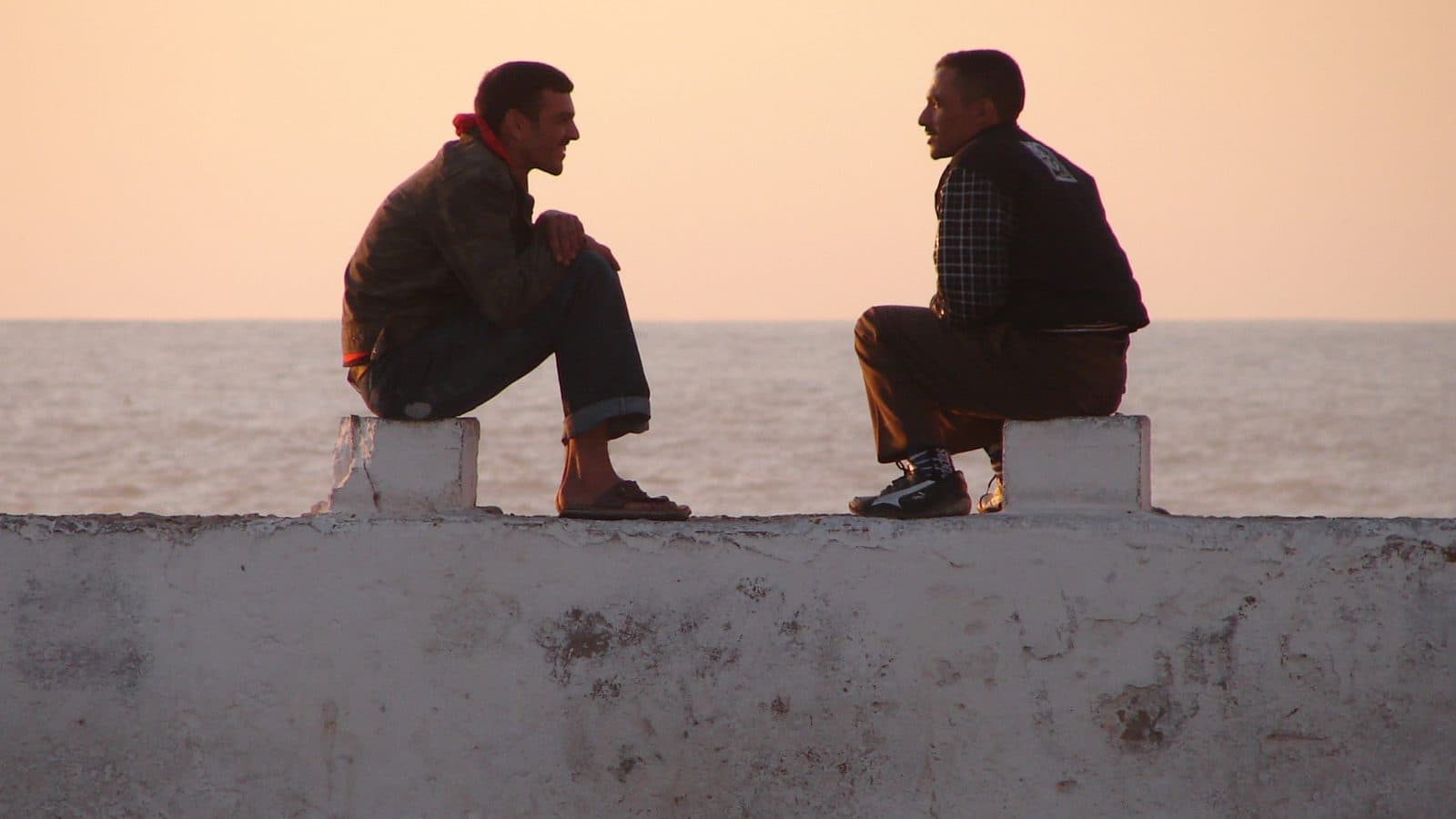 Two men talking on the sea wall of Essaouira at sunset