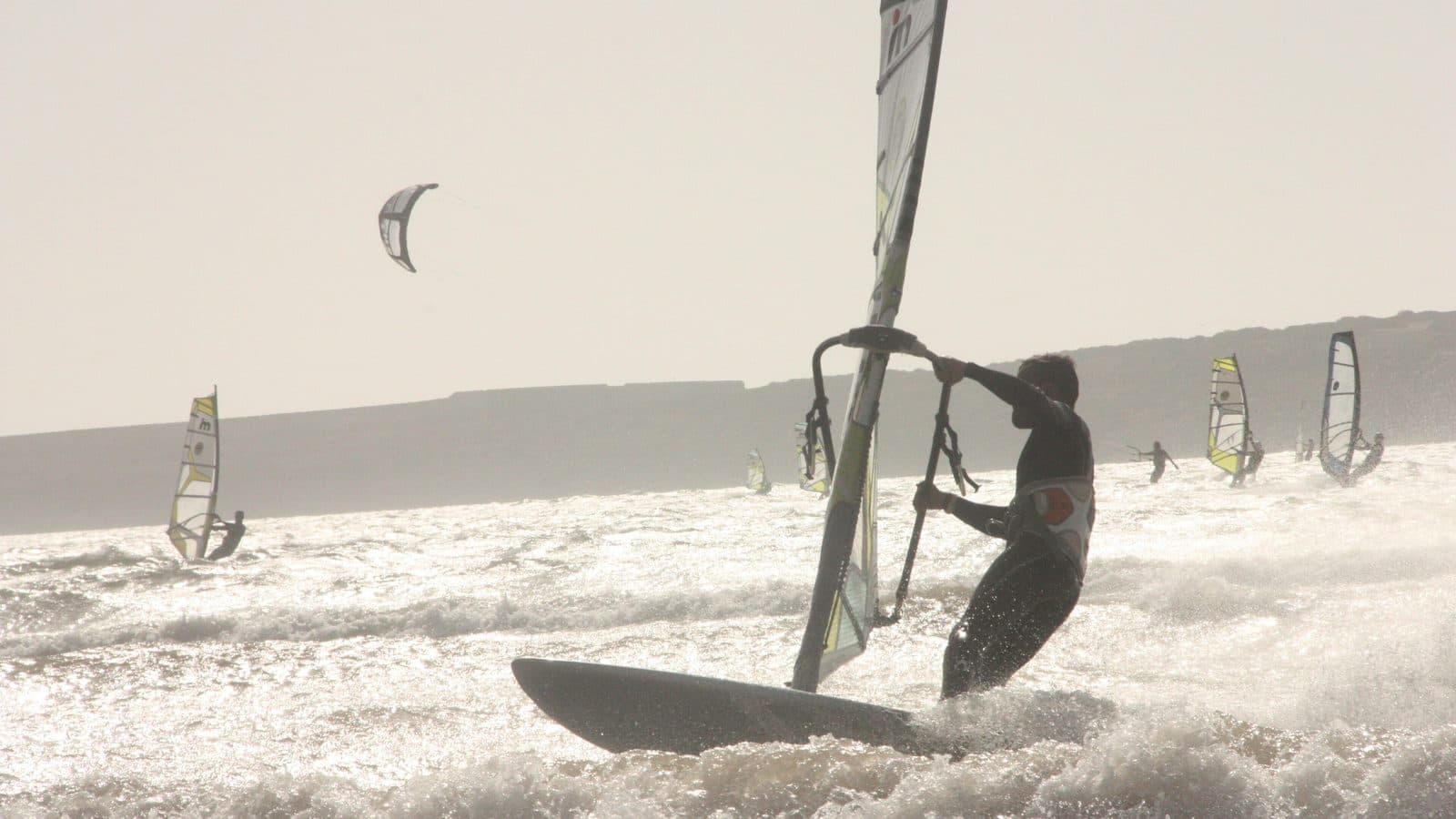 Véliplanchiste et kitesurfeurs dans les vagues de la baie d'Essaouira