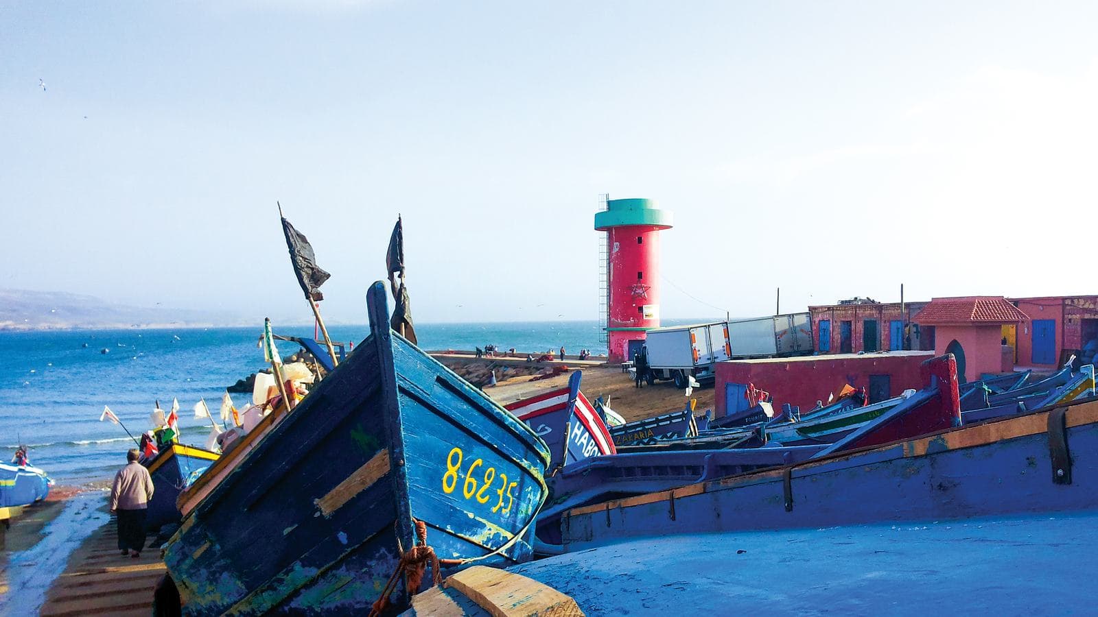 Des barques de pêche bleues tirées sur le quai du petit port d'Imsouane