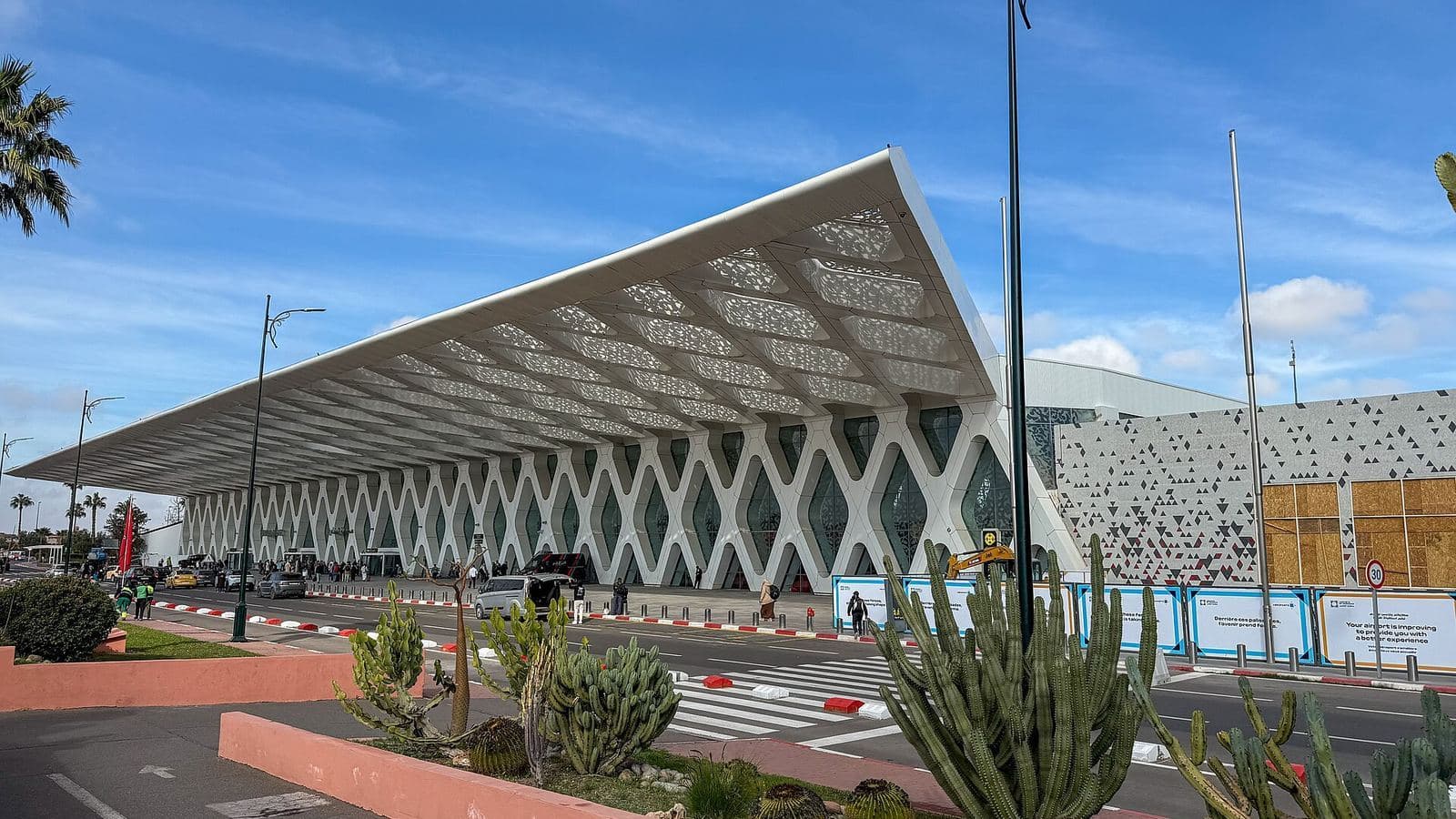 La façade ajourée blanche du terminal de l'aéroport Marrakech Menara sous un ciel bleu