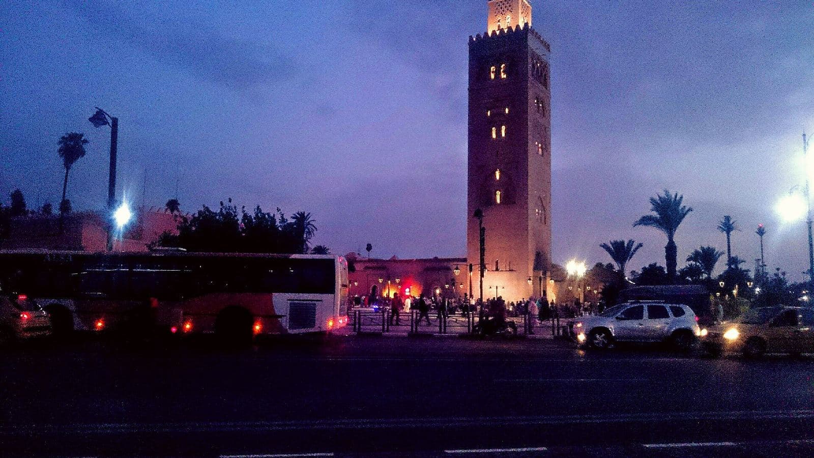 Le minaret de la Koutoubia illuminé au crépuscule au-dessus d’une rue calme de Marrakech