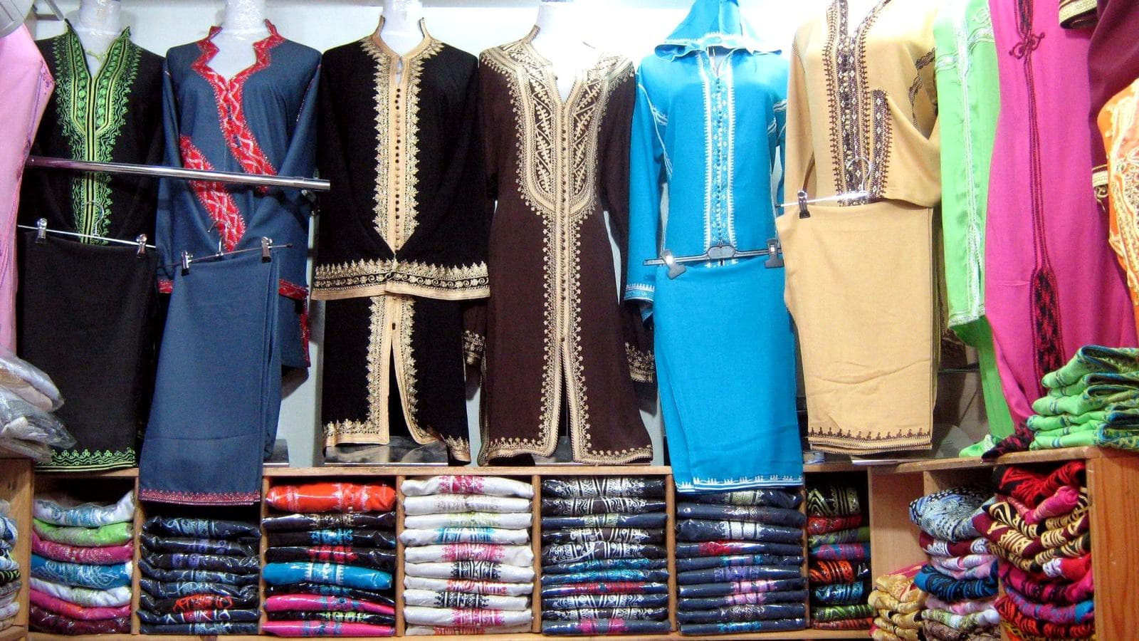 Des caftans et djellabas colorés suspendus dans une boutique de vêtements d'un souk marocain