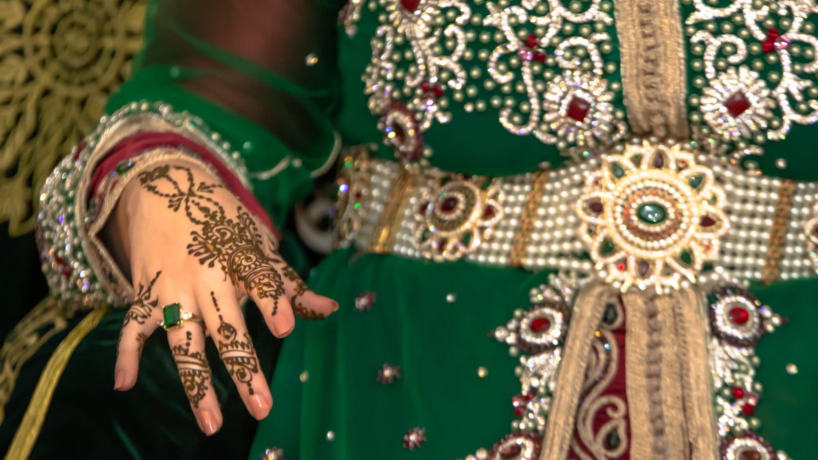 Main de mariée ornée de henné sur un caftan de mariage marocain vert brodé