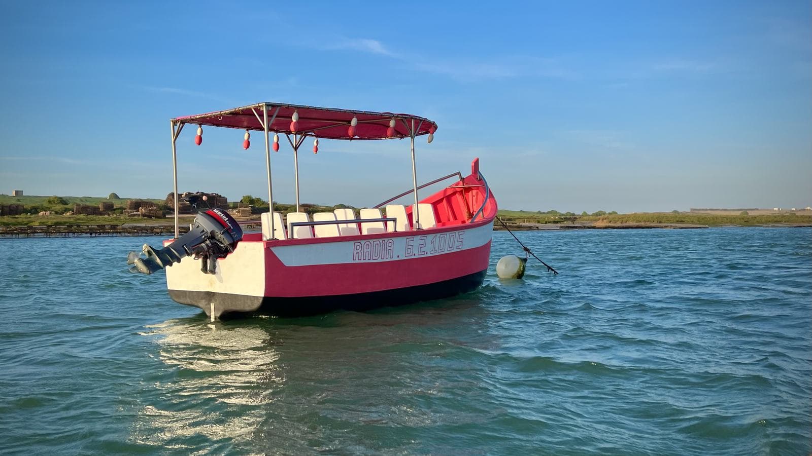 Un petit bateau rouge et blanc sur la lagune turquoise d'Oualidia