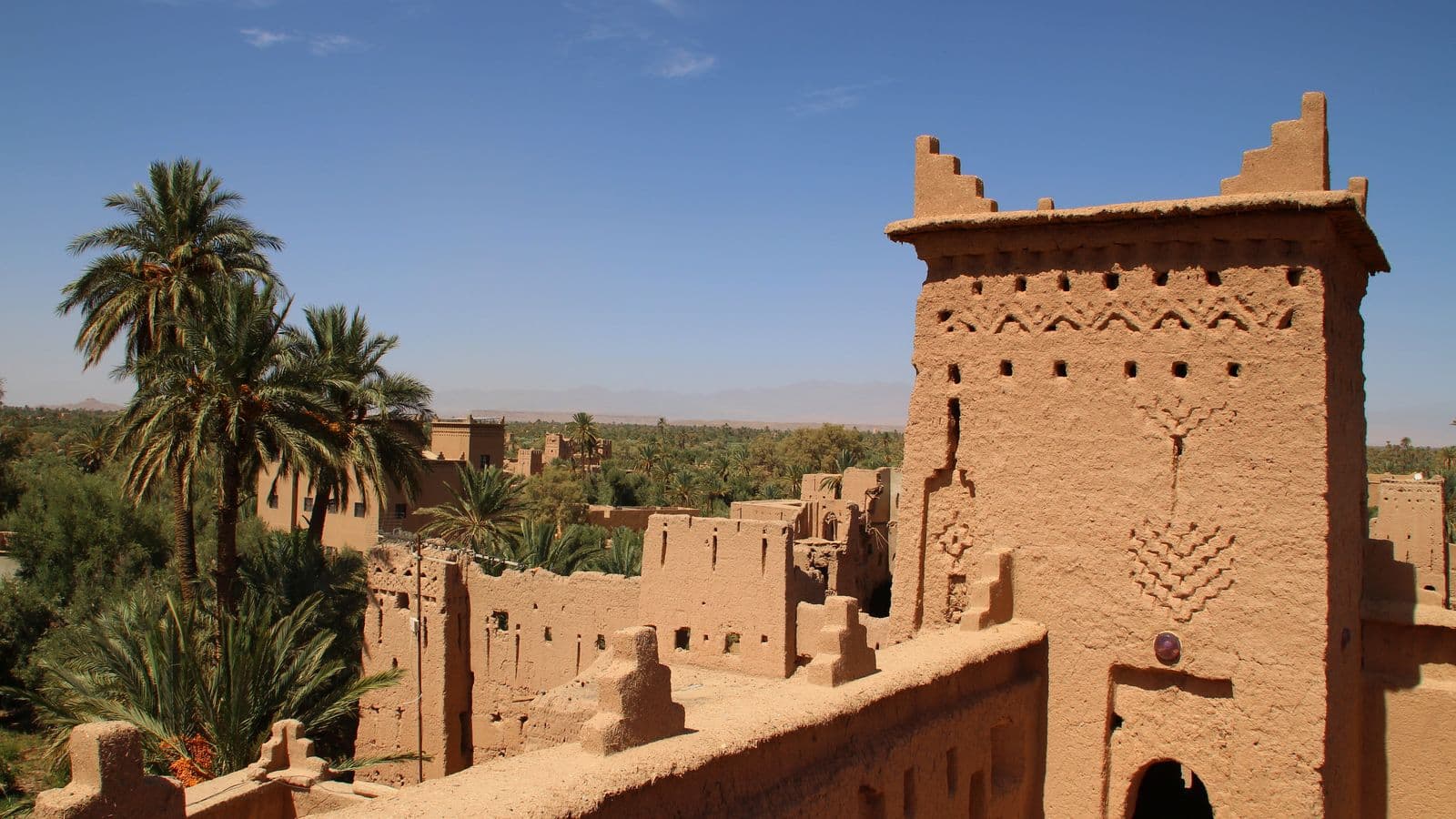 An earth-built kasbah tower among the palm trees of the Skoura oasis