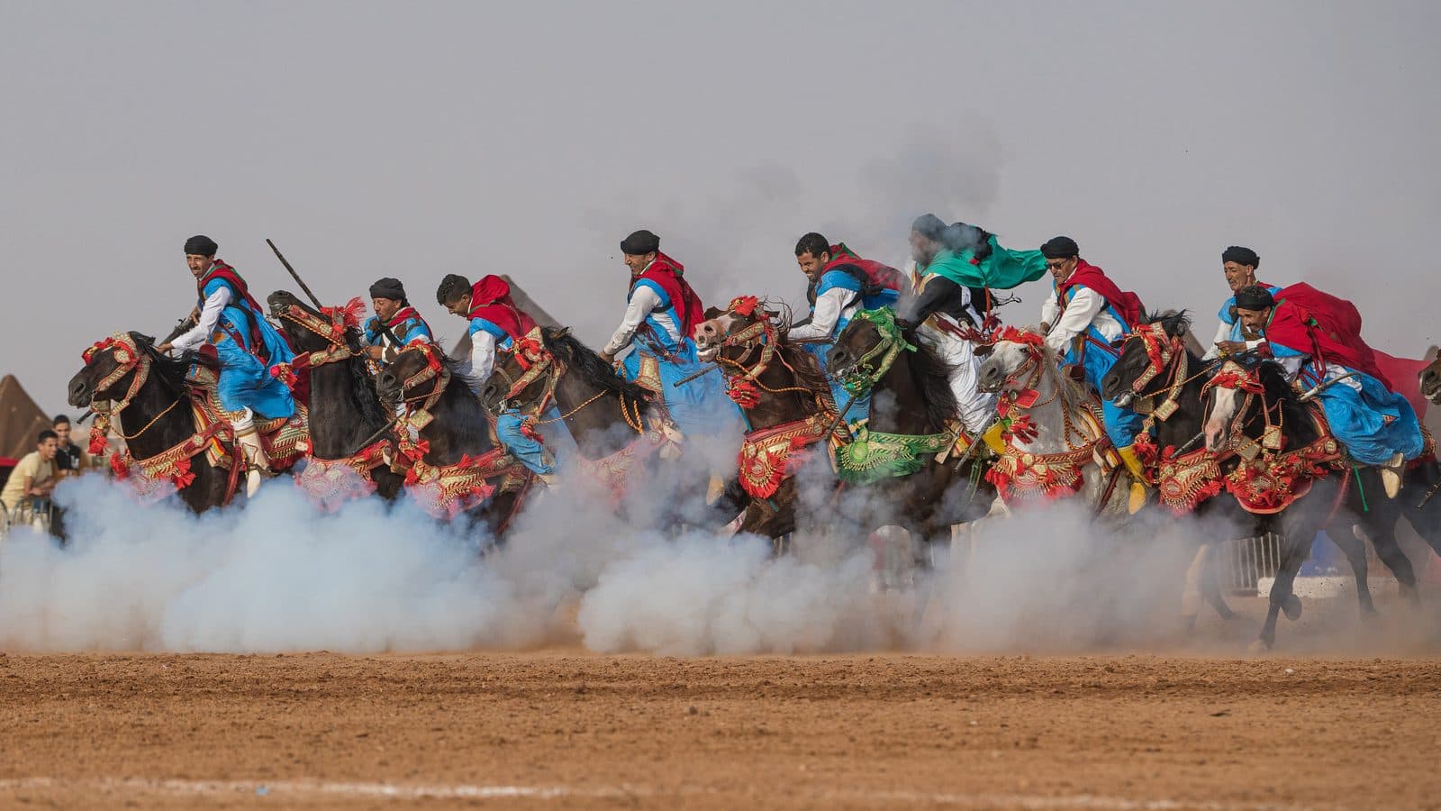 Tbourida riders in colourful robes galloping through gunpowder smoke at the Tan-Tan moussem