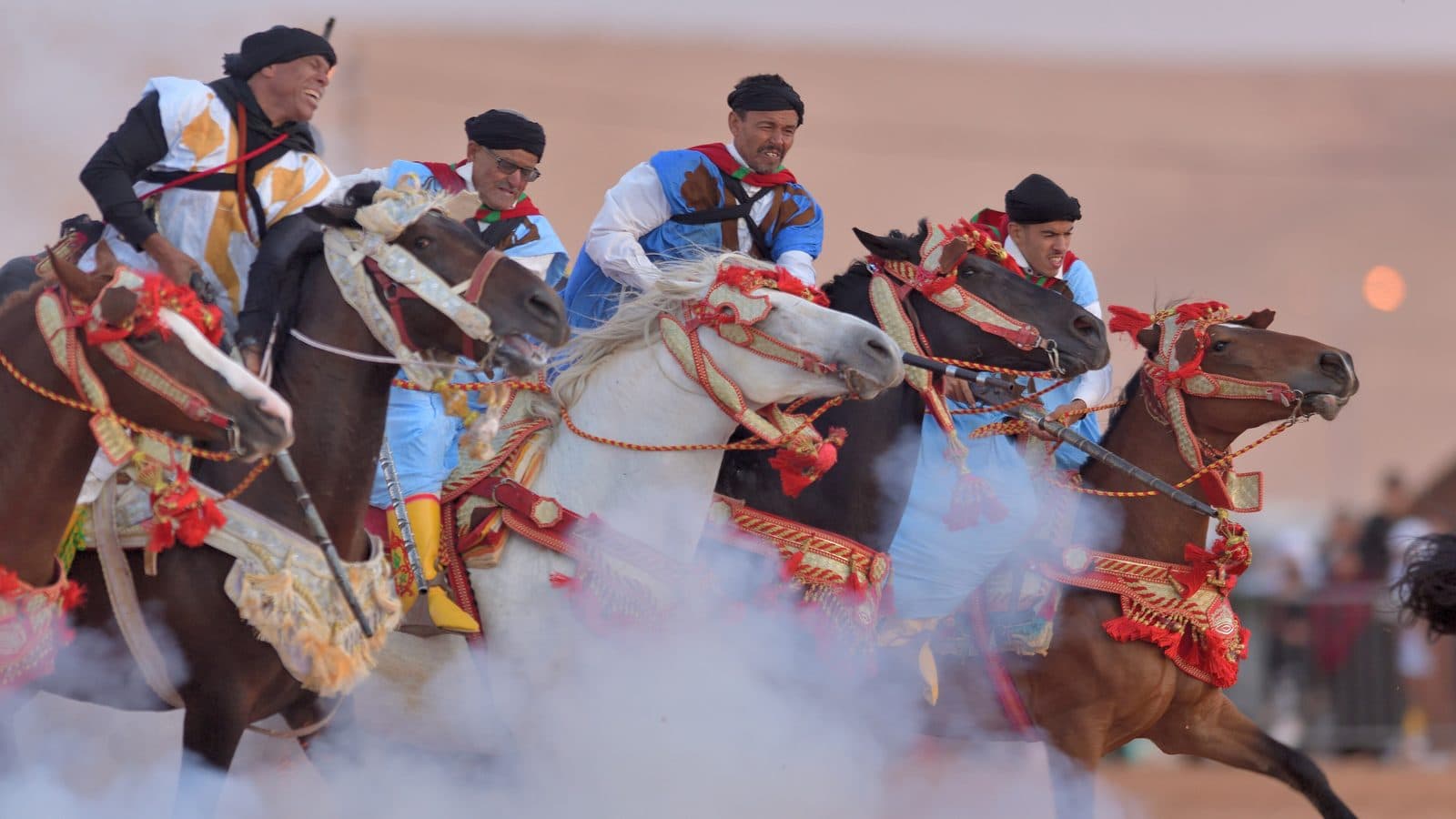 Tbourida riders charging through a cloud of gunpowder smoke at the Tan-Tan moussem