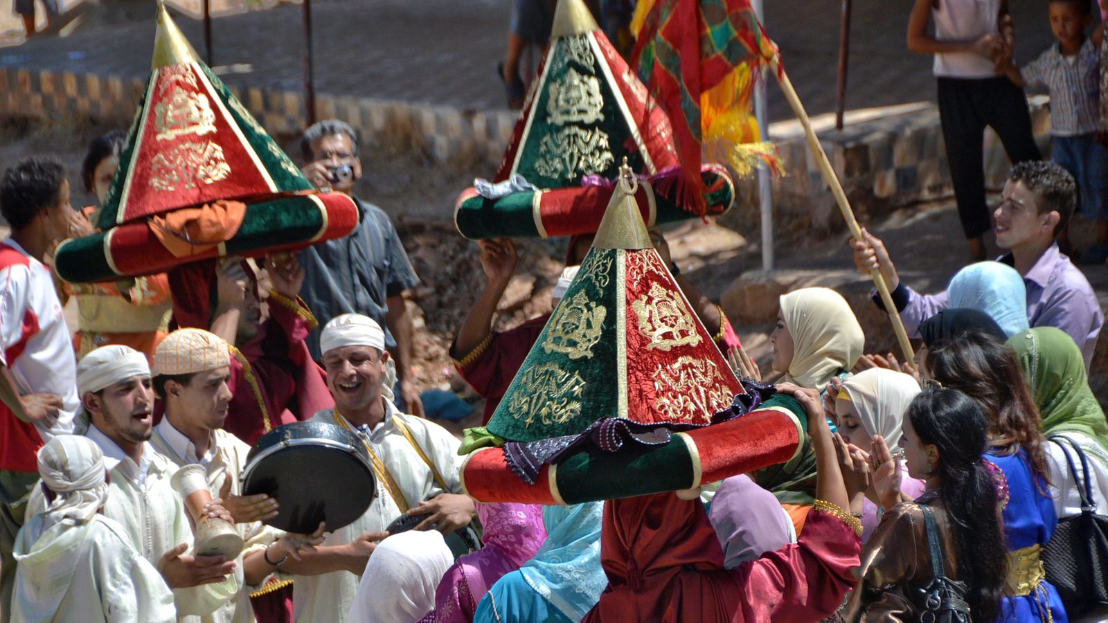 Invités en tenue traditionnelle célébrant un mariage amazigh avec tambours et palanquins décorés