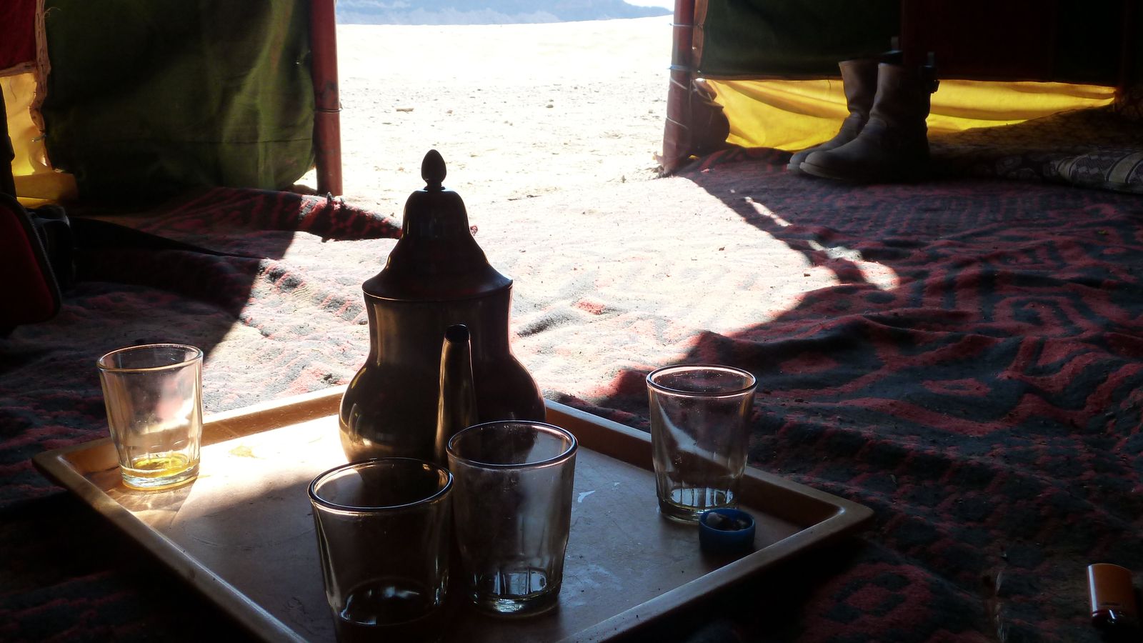 A Moroccan teapot and glasses on a tray inside a desert tent