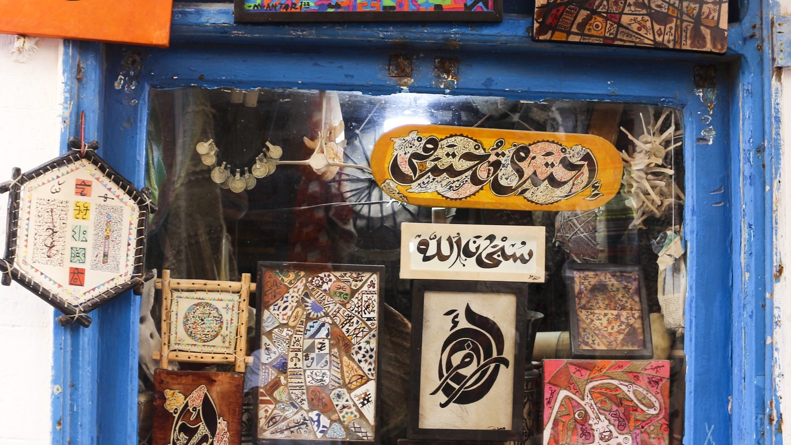 Arabic calligraphy and painted works in the window of a studio in Essaouira