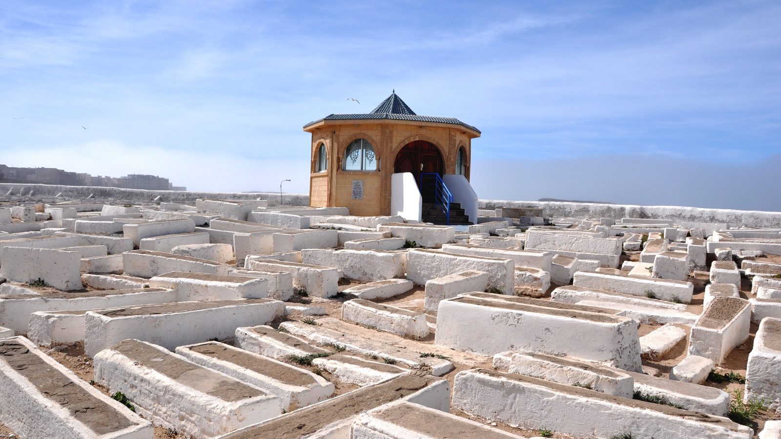 Rangées de tombes blanches dans l'ancien cimetière juif d'Essaouira, avec un petit édifice à coupole en arrière-plan