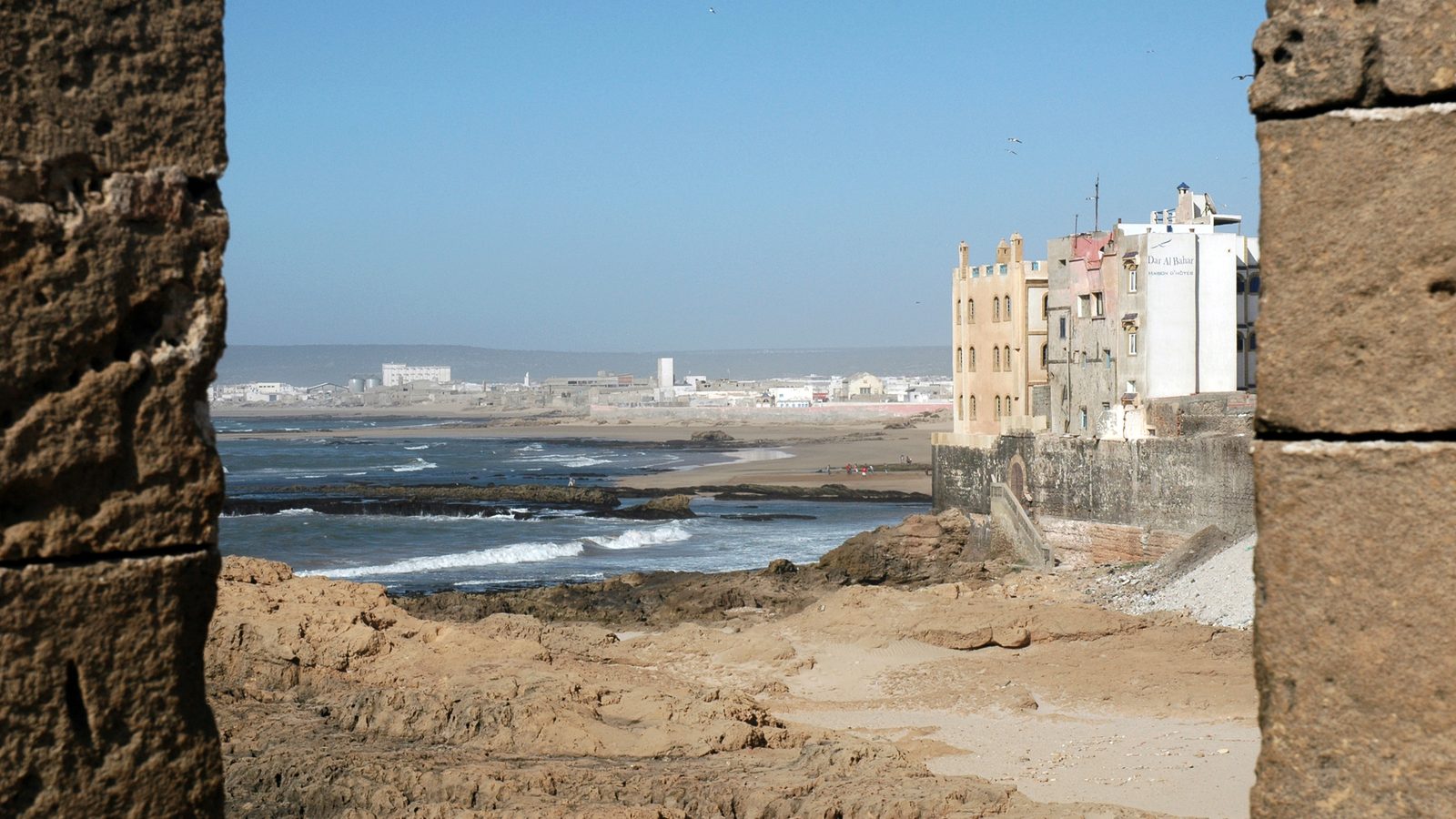 View from the city walls of Essaouira over the rocky shore and the white houses of the Jrayfat quarter