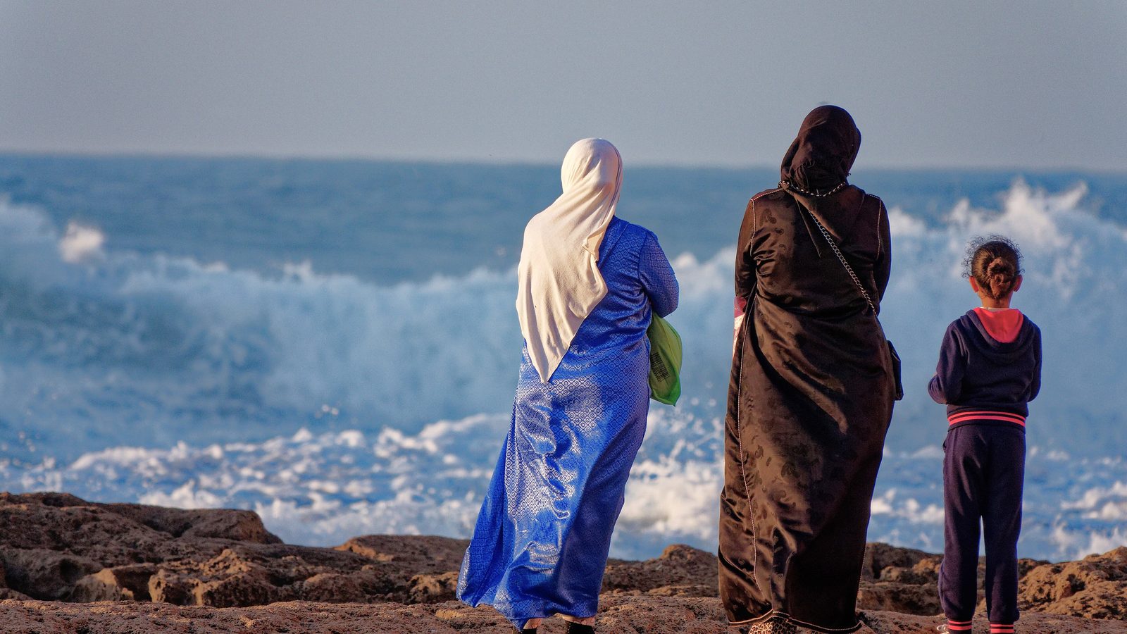 Une famille regarde les vagues se briser sur les rochers à Essaouira
