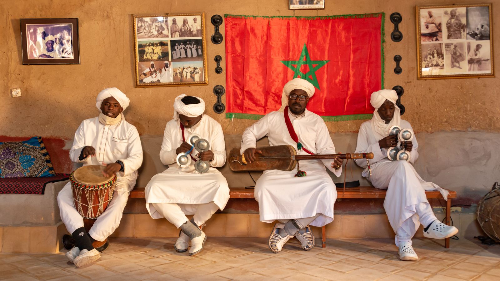 Musiciens gnawa assis en rang avec tambours, crotales et guembri à Khamlia
