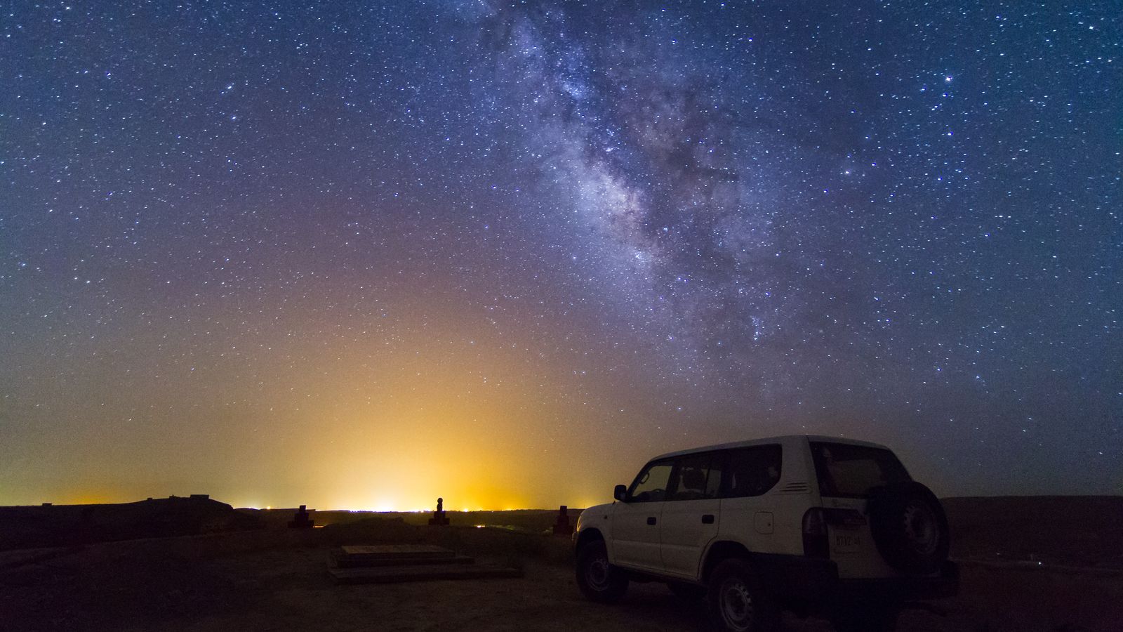 Un ciel étoilé au-dessus d'un 4x4 garé la nuit dans le désert marocain