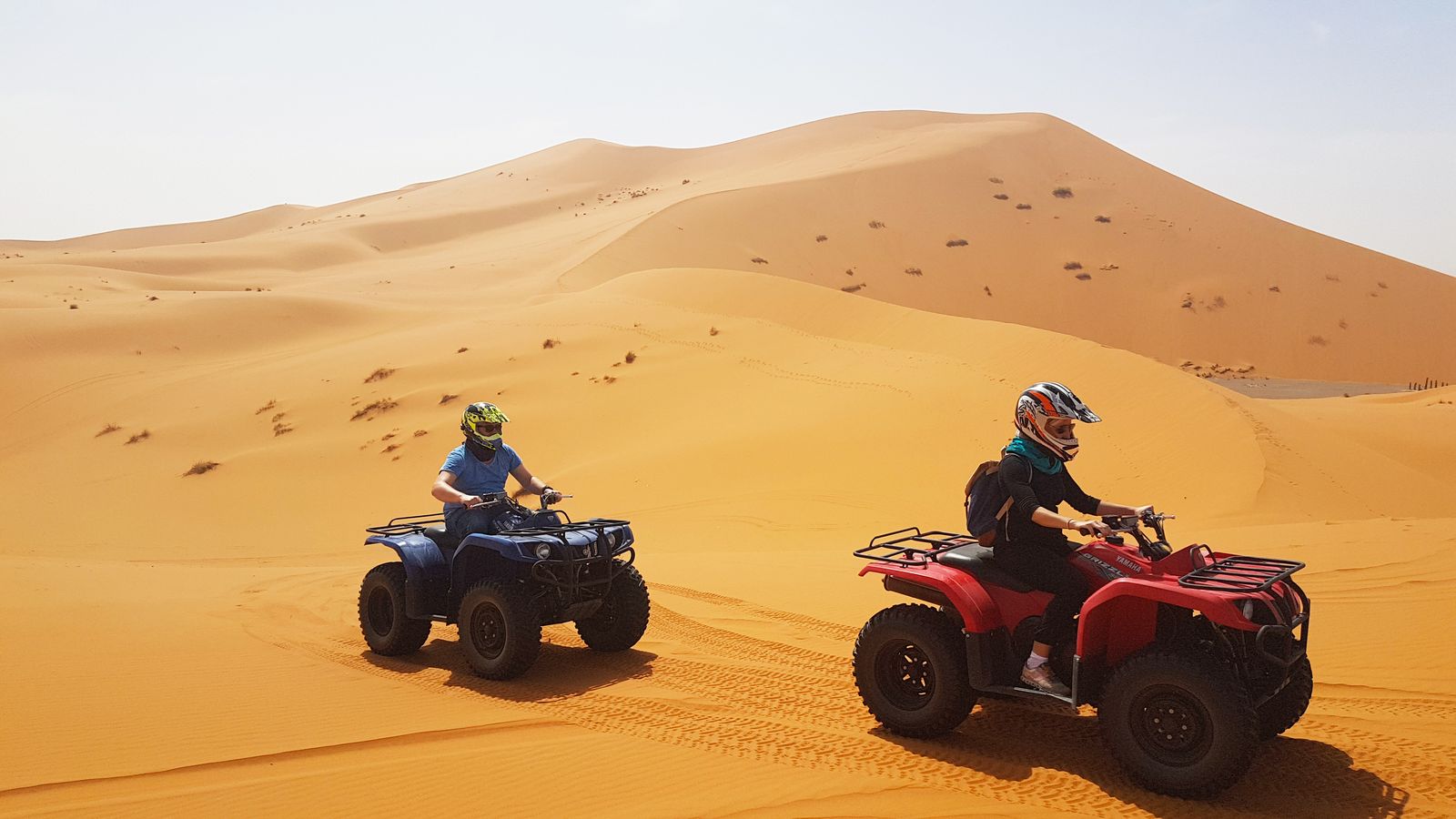 Two quad bikes riding across the orange dunes of Erg Chebbi