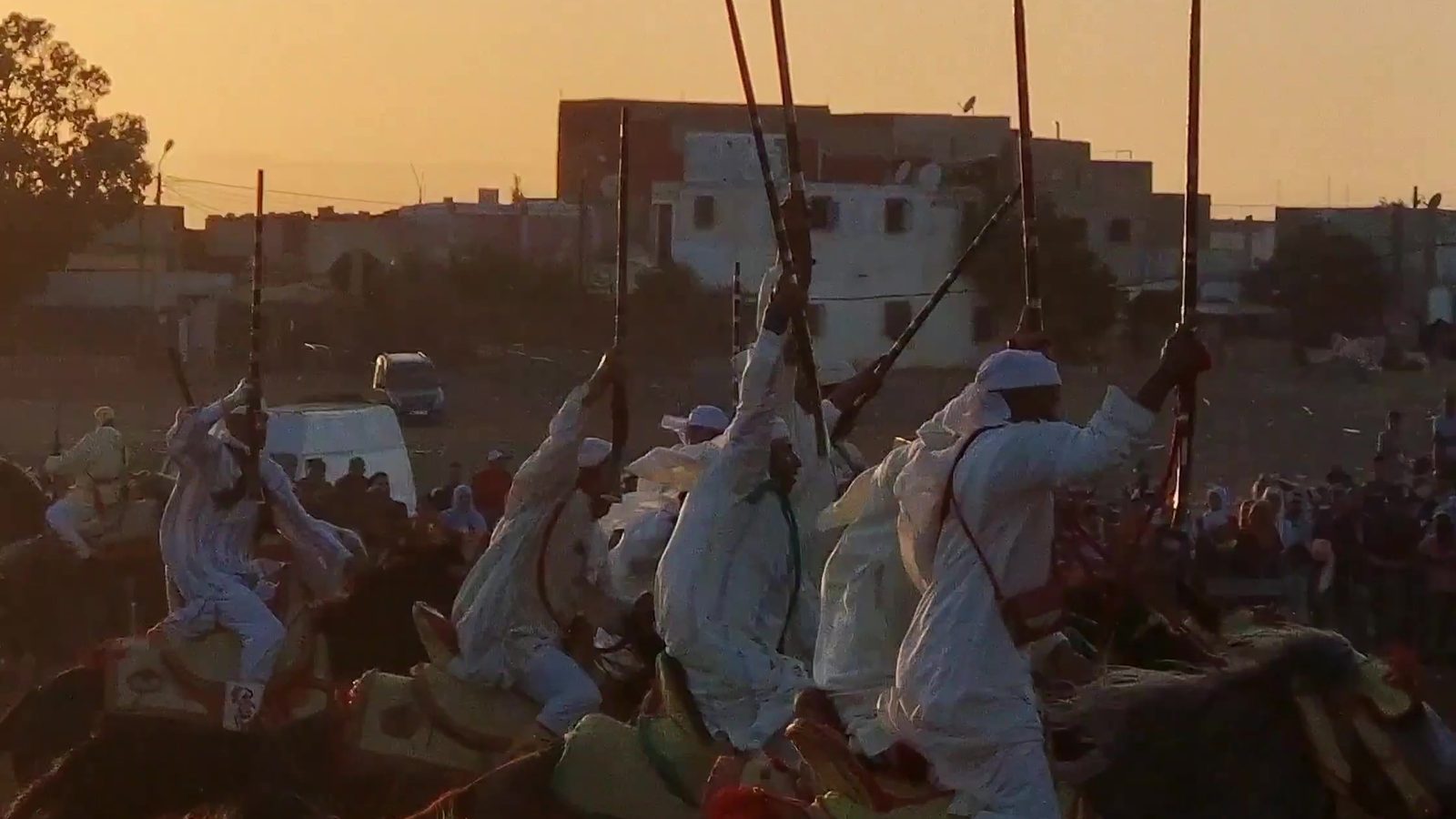 Tbourida riders silhouetted against the sunset at a rural moussem