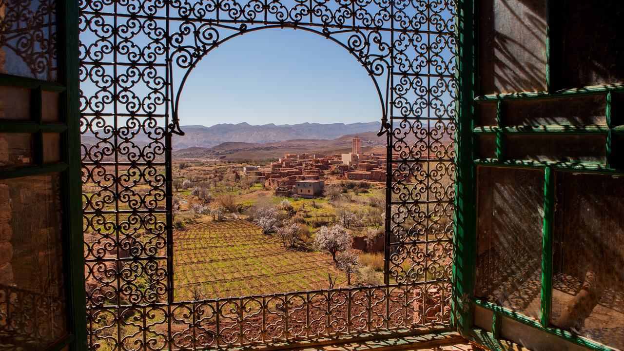Une fenêtre en fer forgé de la kasbah de Telouet encadrant la vallée
